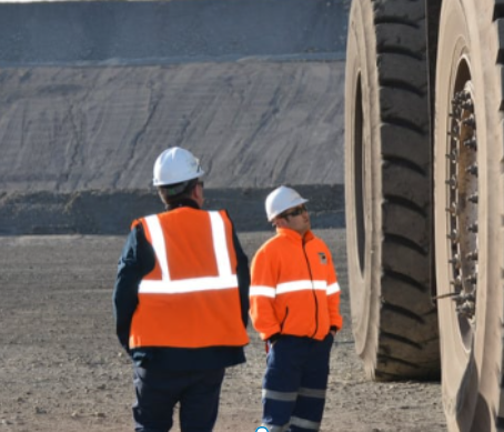 Trabalhadores de mineração em frente a um pneu gigante de máquina de mineração industrial